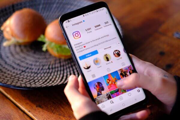 Manos navegando por la app de Instagram en un móvil revisando su estrategia de marketing más reciente